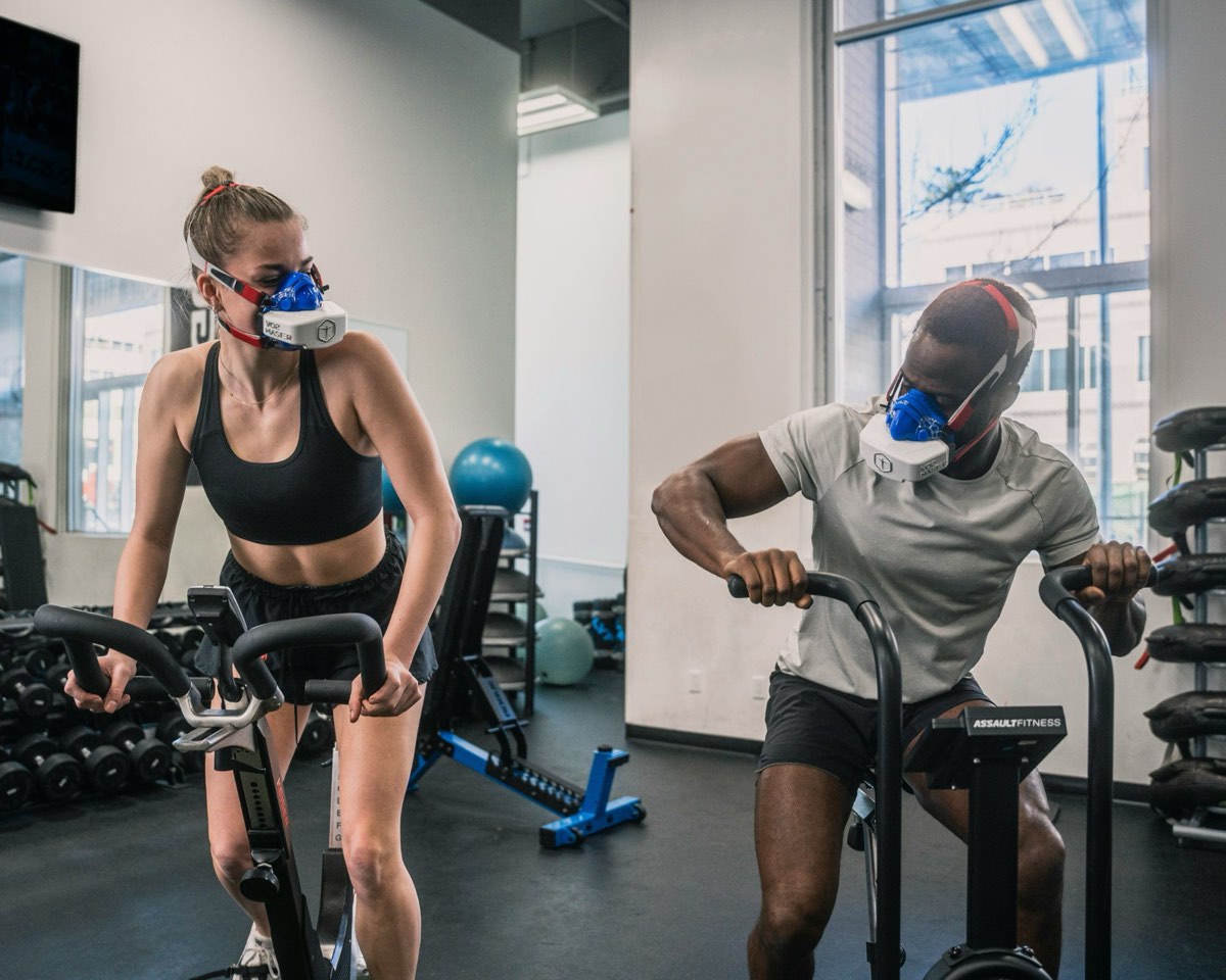 Two athletes on stationary bikes wearing metabolic testing masks during an exercise test
